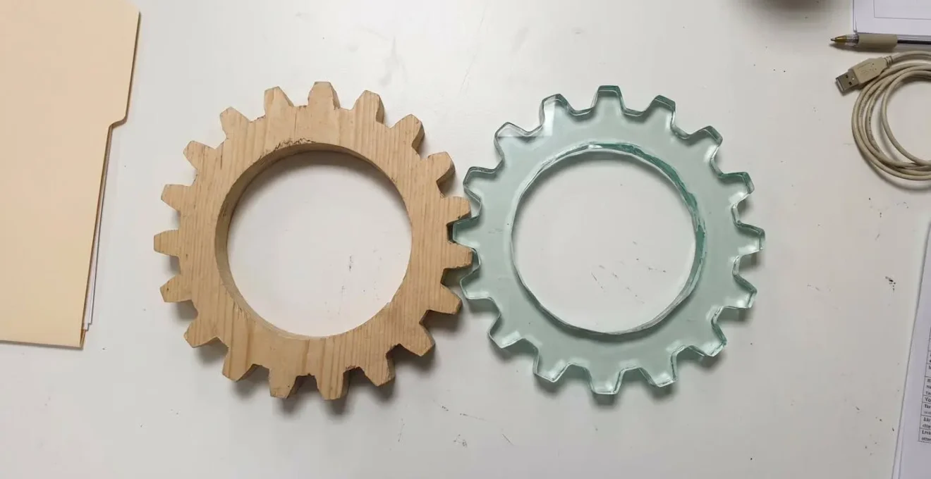 Deux engrenages en bois et verre imbriqués symbolisant l'alignement communication interne et image de marque.